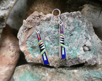 May include: A pair of dangle earrings with a geometric design. The earrings are made of silver and feature a variety of colorful stones, including blue, green, red, and black.