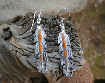 May include: A pair of silver earrings with a feather design. The feathers are inlaid with orange and turquoise stones.