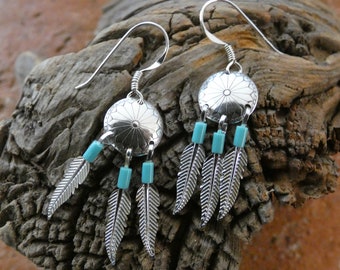 May include: Silver earrings with turquoise beads and feather charms. The earrings are in the shape of a dreamcatcher.