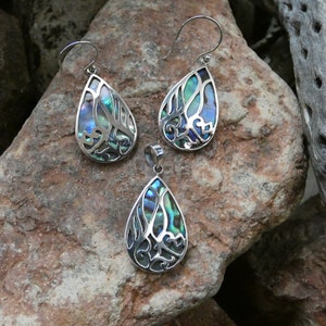 May include: A set of three silver earrings and a pendant featuring a teardrop-shaped design with a blue, green, and iridescent abalone shell inlay.