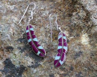 May include: A pair of sterling silver earrings featuring a purple and white feather design. The earrings are made with inlaid turquoise and purple stones.