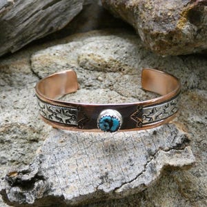 Peut inclure: Un bracelet en cuivre avec un motif en argent incrusté et une pierre turquoise au centre.