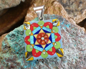 May include: A square pendant with a colorful geometric design made of inlaid stones. The pendant is made of silver and features a variety of colors, including red, blue, green, yellow, and white.