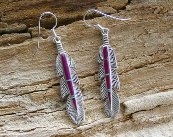 May include: A pair of silver dangle earrings with a feather design. The feathers are inlaid with purple and turquoise stones.