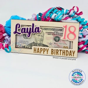 May include: Wooden money holder with a slot for a bill, personalized with the name "Layla" in purple and the number "18" in pink. The text "Happy Birthday" is engraved on the front.