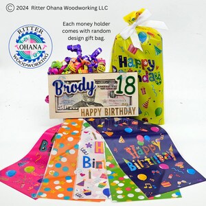 May include: A wooden money holder with the name "Brody" and the number "18" on it. The holder is decorated with a $50 bill and the words "Happy Birthday". The holder comes with a yellow gift bag with the words "Happy Birthday" on it and a variety of colorful gift bags with different birthday designs.