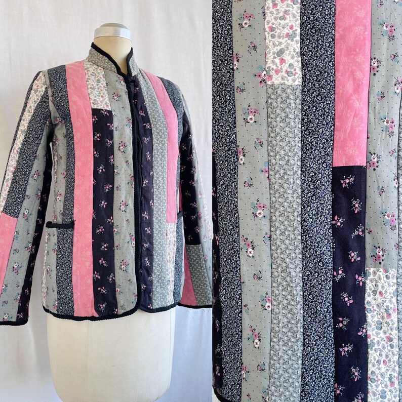 May include: A quilted jacket with a vertical striped pattern in shades of pink, black and grey. The jacket has a mandarin collar and a zip closure.