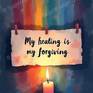 Può includere: Un pezzo di carta bianco con il testo "My healing is my forgiving" appeso a uno spago con mollette. Una candela accesa si trova sotto la carta, con uno sfondo arcobaleno sfocato.