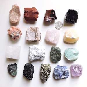 May include: A collection of 15 different types of crystals and stones, including amethyst, rose quartz, clear quartz, citrine, and more. The crystals are arranged in a grid pattern on a white background.
