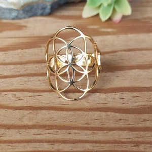 Puede incluir: Un anillo de color dorado con un diseño geométrico que se asemeja a una flor de la vida.