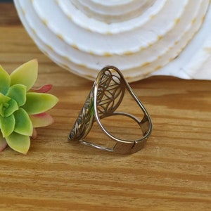 May include: A silver ring with a geometric design. The ring is open and adjustable.