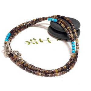 May include: A multi-strand necklace made of brown and turquoise beads with a silver clasp.