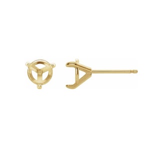 May include: A pair of gold-tone earring settings for round gemstones. The settings are designed to hold a stone securely in place.