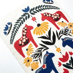 May include: A white background with a pattern of red and blue stylized horses, green leaves, and yellow and red flowers. The horses are traditional Swedish Dala horses.