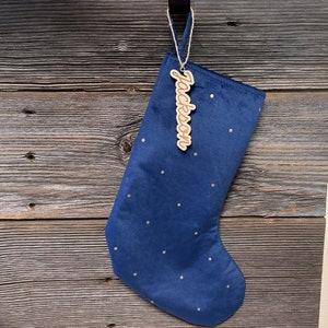 May include: A blue velvet Christmas stocking with gold polka dots and a wooden tag that says "Jackson".