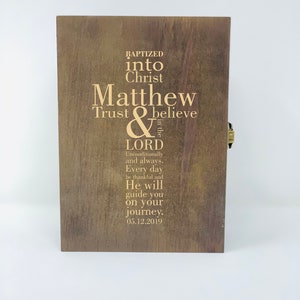 May include: A wooden box with a gold latch, engraved with the text "Baptized into Christ Matthew Trust & believe in the LORD Unconditionally and always. Every day be thankful and He will guide you on your Journey. 05.12.2019".