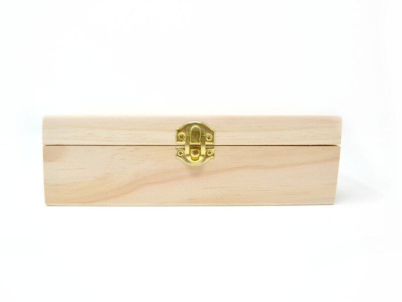 Op de afbeelding: Een houten doos met een scharnierend deksel en een messing sluiting. De doos is gemaakt van licht hout en heeft een natuurlijke afwerking.