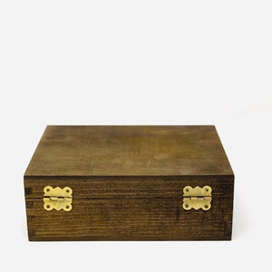 May include: A dark brown wooden box with brass hinges. The box has a smooth, polished finish and is closed.