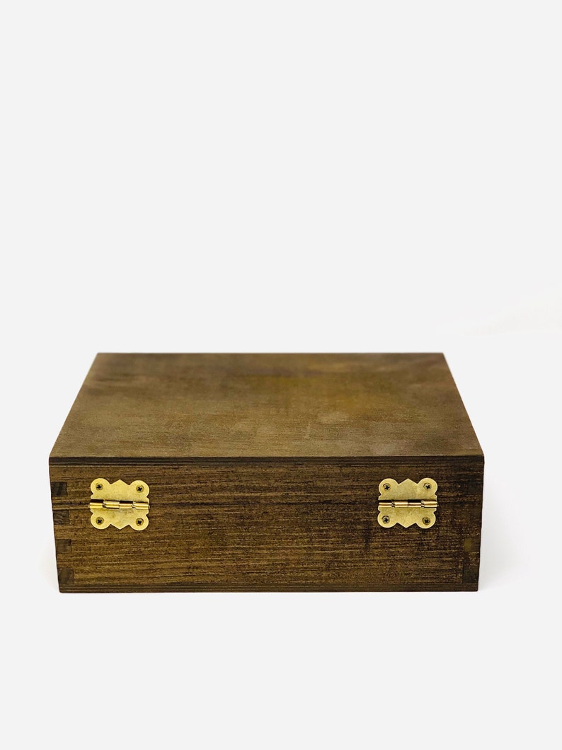 May include: A dark brown wooden box with brass hinges. The box has a smooth, polished finish and is closed.