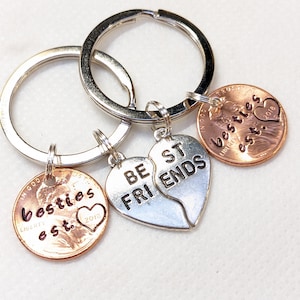 May include: Keychains with silver rings and copper penny charms. One keychain has a split heart pendant with "BE FRIENDS" on it. Two other keychains have pennies with "besties est. 2018" engraved on them.