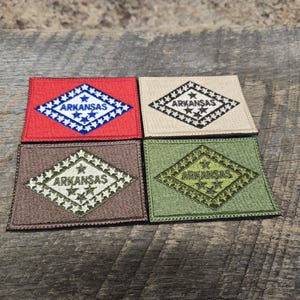 May include: Four embroidered patches featuring the Arkansas state flag. The patches are in red, beige, brown, and green.