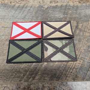 Puede incluir: Cuatro parches bordados con un diseño de cruz diagonal. Los parches están en diferentes combinaciones de colores: rojo y blanco, negro y marrón, negro y verde, y negro y camuflaje.