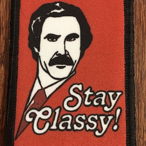 Könnte beinhalten: Ein roter Stoff-Patch mit schwarzem Rand, der ein Cartoon-Bild eines Mannes mit Schnurrbart und den Text "Stay Classy!" zeigt.