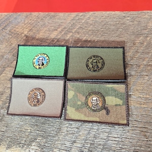 May include: Four embroidered patches featuring a portrait of George Washington. The patches are in different colours and patterns, including green, brown, and camouflage.