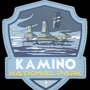 以下が含まれることがあります： 「KAMINO NATIONAL PARK」という文字と、惑星の上空を飛ぶ宇宙船と都市のスタイリッシュな画像が描かれた青と白のパッチです。