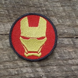 Puede incluir: Un parche bordado de Iron Man rojo y amarillo con borde negro.