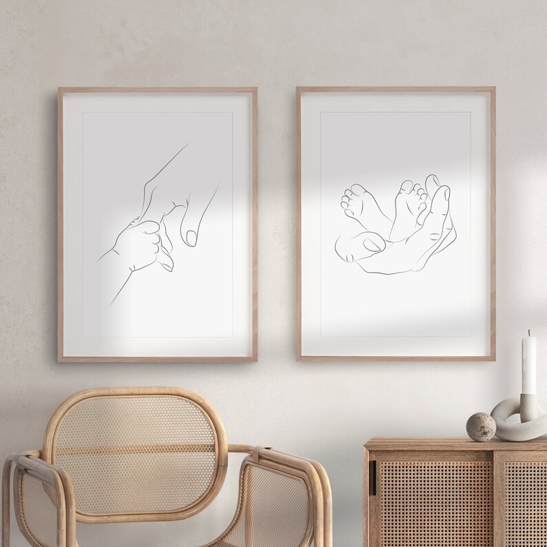 Puede incluir: Dos grabados enmarcados de arte lineal. Uno representa una mano sosteniendo la mano de un beb&eacute;, el otro muestra los pies del beb&eacute; en una mano. Los grabados est&aacute;n en marcos de madera clara, creando una est&eacute;tica minimalista y conmovedora.