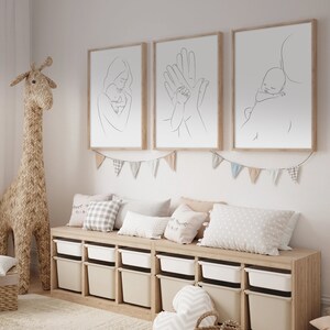 Puede incluir: Tres impresiones minimalistas de arte lineal en marcos de madera colgadas en una pared blanca. Las impresiones representan a una madre sosteniendo un beb&eacute;, dos manos sosteni&eacute;ndose mutuamente y un padre sosteniendo un beb&eacute;. Las impresiones est&aacute;n sobre un banco de madera con contenedores de almacenamiento y almohadas.