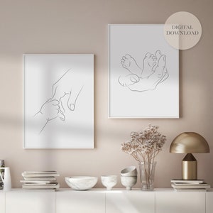 Puede incluir: Dos grabados enmarcados de arte lineal minimalista. Uno representa una mano sosteniendo la mano de un beb&eacute;, el otro muestra una mano acunando los pies del beb&eacute;. Los grabados est&aacute;n en marcos blancos con un fondo neutro. El texto "DESCARGA DIGITAL" est&aacute; en un c&iacute;rculo en el grabado de la derecha.