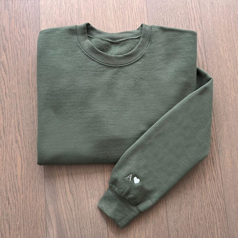 May include: A green sweatshirt with a white letter A and a heart on the sleeve.