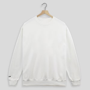 May include: A white crew neck sweatshirt with a small black heart on the left sleeve.