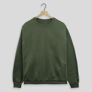 May include: A plain, dark green crew neck sweatshirt with long sleeves.