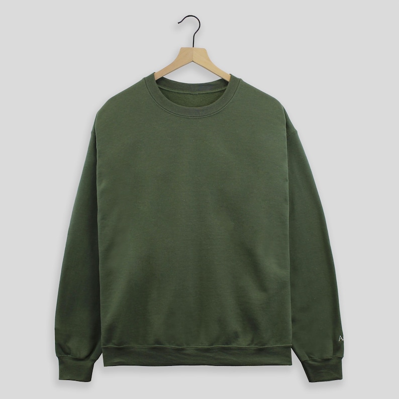 May include: A plain, dark green crew neck sweatshirt with long sleeves.