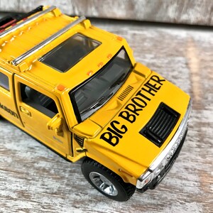 May include: Yellow toy Hummer with a black "BIG BROTHER" decal on the hood. The toy has a black grill, black wheels, and a sunroof.