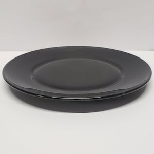 May include: A black ceramic plate with a slightly raised rim.