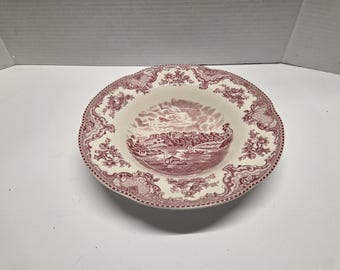 May include: A round, off-white ceramic bowl with a maroon landscape scene in the center. The rim features a floral and scroll design. The bowl has a scalloped edge and is suitable for serving soups or side dishes.