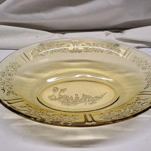 May include: A yellow glass serving bowl with a floral design. The bowl has a scalloped edge and a raised design in the centre.