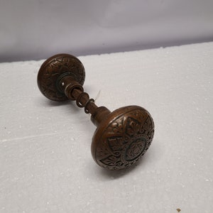 May include: A pair of antique door knobs with intricate floral designs. The knobs are made of a dark metal and have a worn finish.
