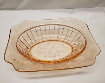 May include: A vintage pink glass serving bowl with a square shape and a scalloped edge. The bowl has a delicate floral pattern etched into the glass.