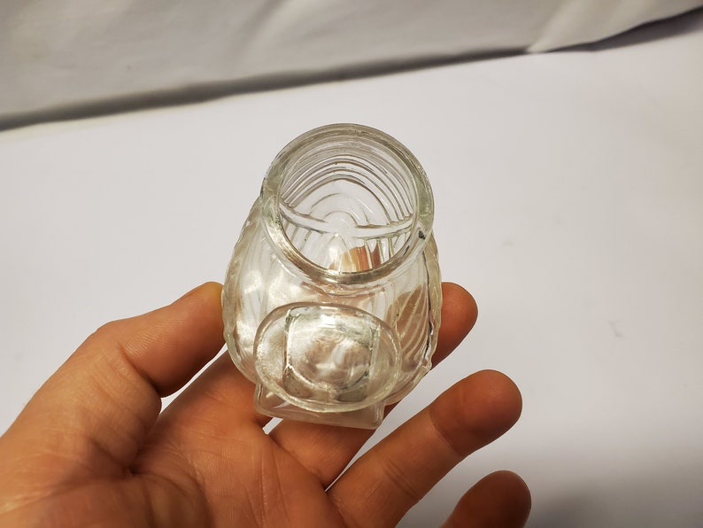 May include: A clear glass jar with a textured surface. The jar has a wide mouth and a rounded bottom.