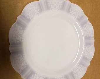 May include: A white, scalloped-edge plate with a delicate floral design in a light lavender hue.