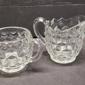 Peut inclure: Un ensemble de crémier et de sucrier en verre transparent avec un motif en diamant. Le crémier a une poignée et un bec verseur. Le sucrier a deux poignées.