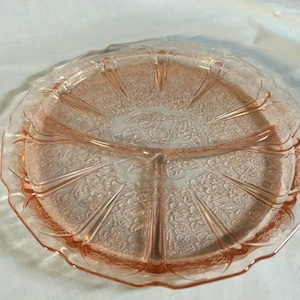 May include: A pink glass serving dish with a scalloped edge and a floral design. The dish is divided into four sections.