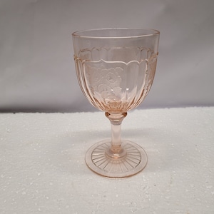 Könnte beinhalten: Ein rosa Glaskelch mit floralem Muster und einem geriffelten Fuß.