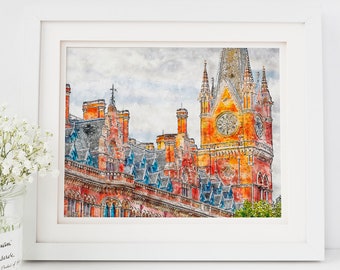 May include: Watercolor print of a historic building with a clock tower, framed in white. The building features red brick, blue roof tiles, and ornate architectural details. The artwork is displayed on a white surface with a vase of white flowers.