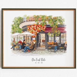 May include: A framed watercolor illustration of a corner cafe with outdoor seating, featuring people at tables under umbrellas, vibrant autumn foliage, and a dark storefront. The text "Our First Date" and "11 15 22" is printed at the bottom.